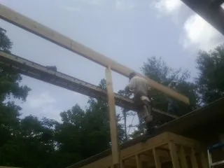Carpenter setting a ridge beam over a new addition frame — Ice Dam Removal by Roofing Brothers in Aston