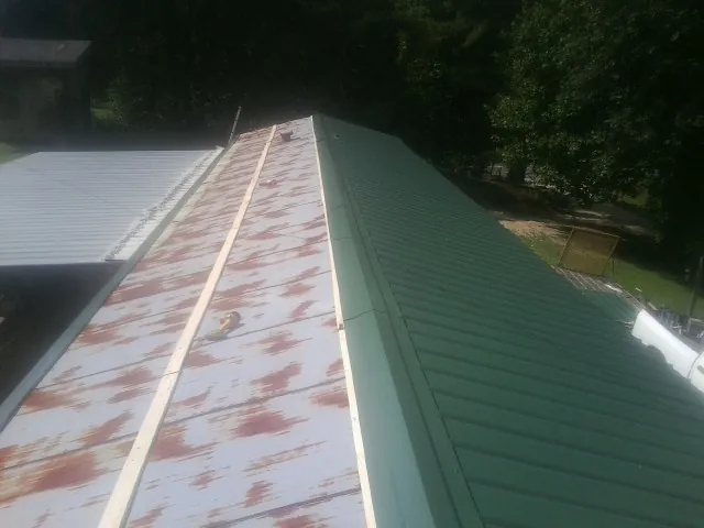 Old rusted panels beside newly installed green metal roofing — Wind Damage Roof Repair by Roofing Brothers in Aston
