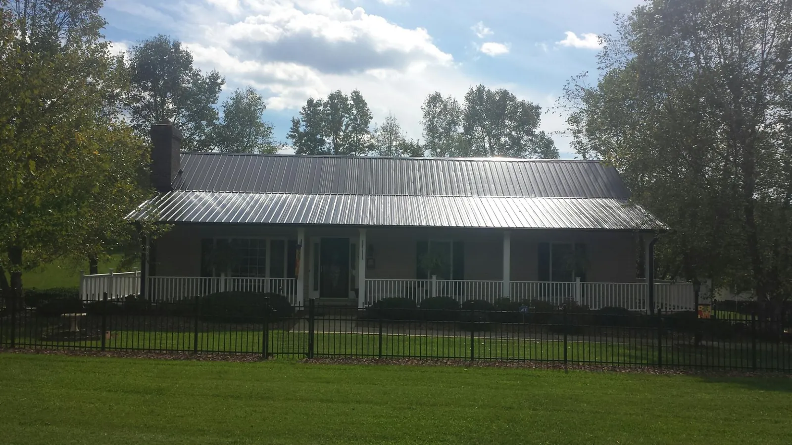 Gray metal roof on a brick ranch with a full width front porch — Gutter Guard Installation work by our crew in Aston