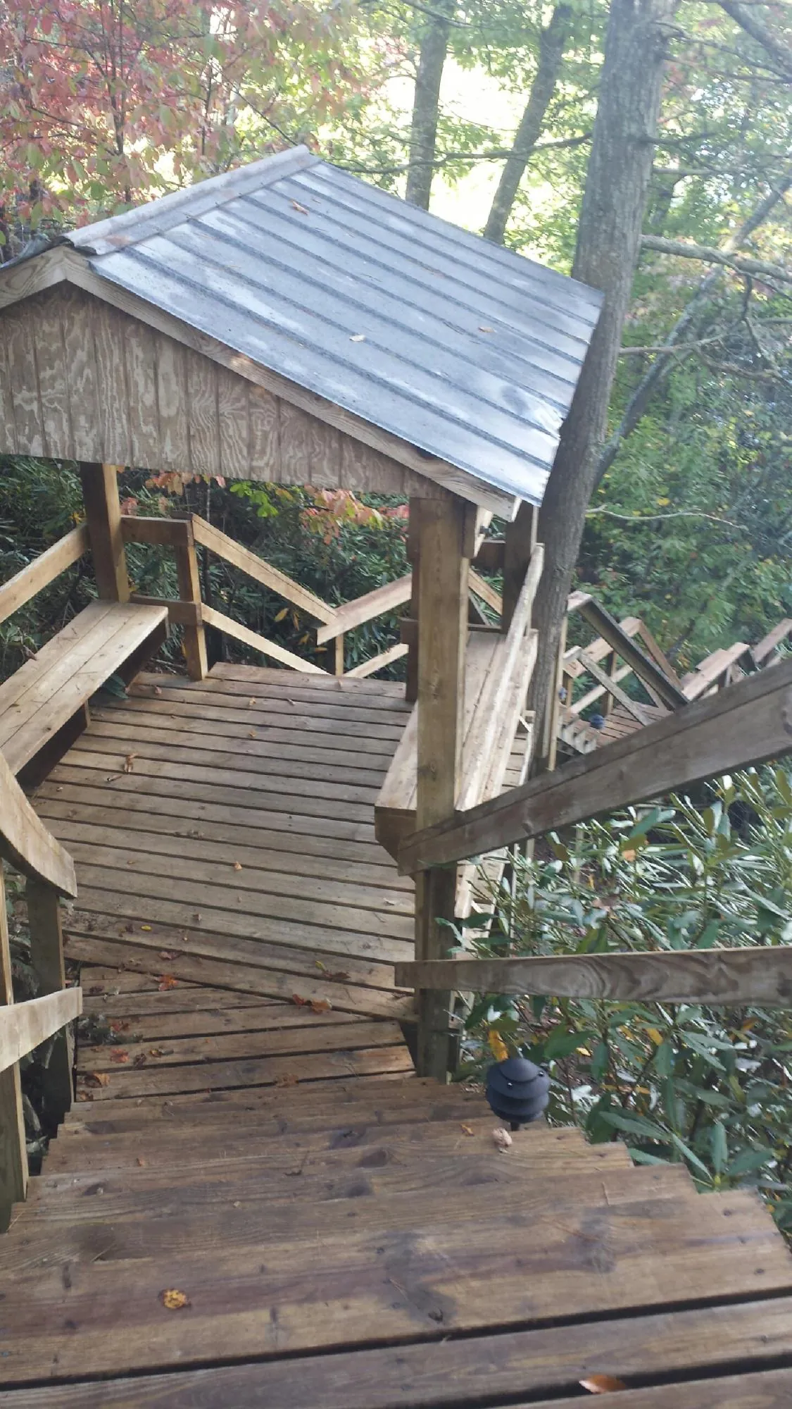 Metal roofed shelter over wooden steps on a wooded walkway — Skylight Repair & Installation work by our crew in Aston