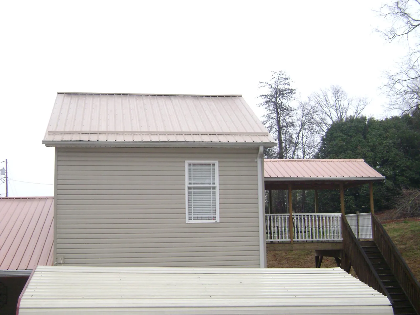 Tan metal roofs on a two story addition and attached porch, from a Roof Replacement job in Aston