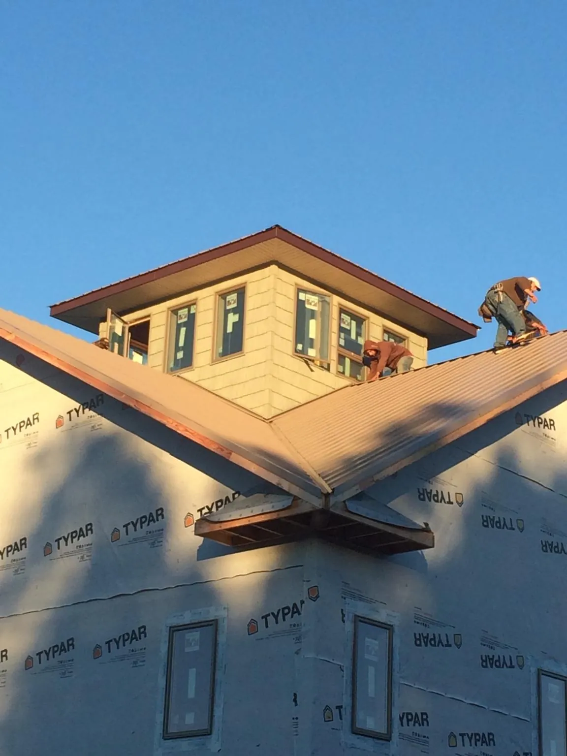 Roofers working around a rooftop cupola on a new metal roof at sunset — Roof Waterproofing in Aston by Roofing Brothers